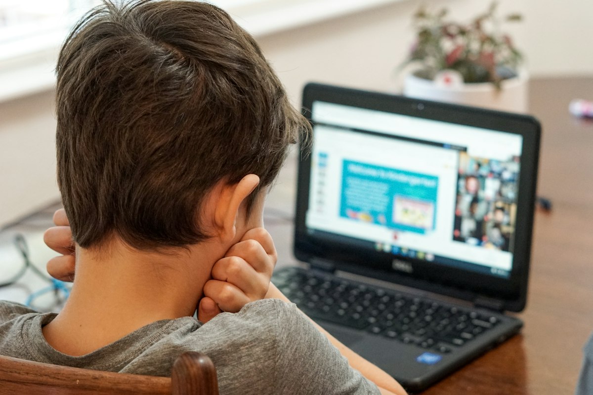 Boy in a live small-group class with his teacher and classmates on screen